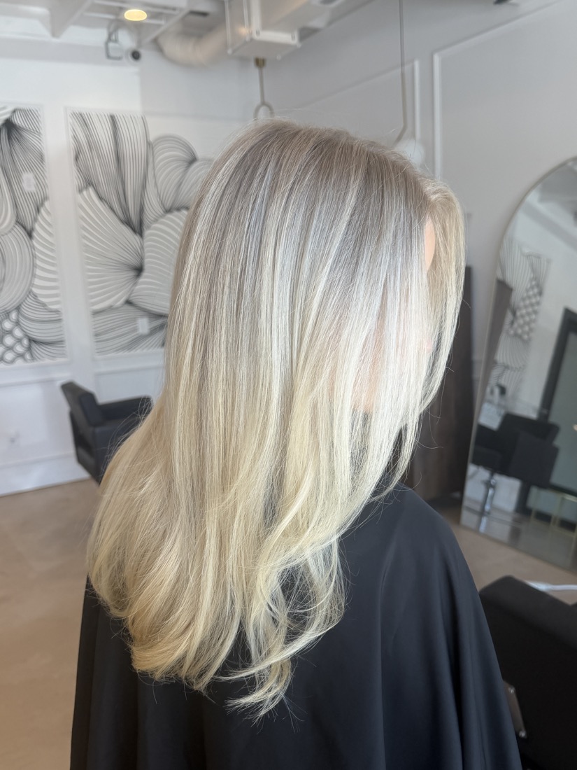 Bright platinum, straight and glossy, finished at the chair in a black cape.