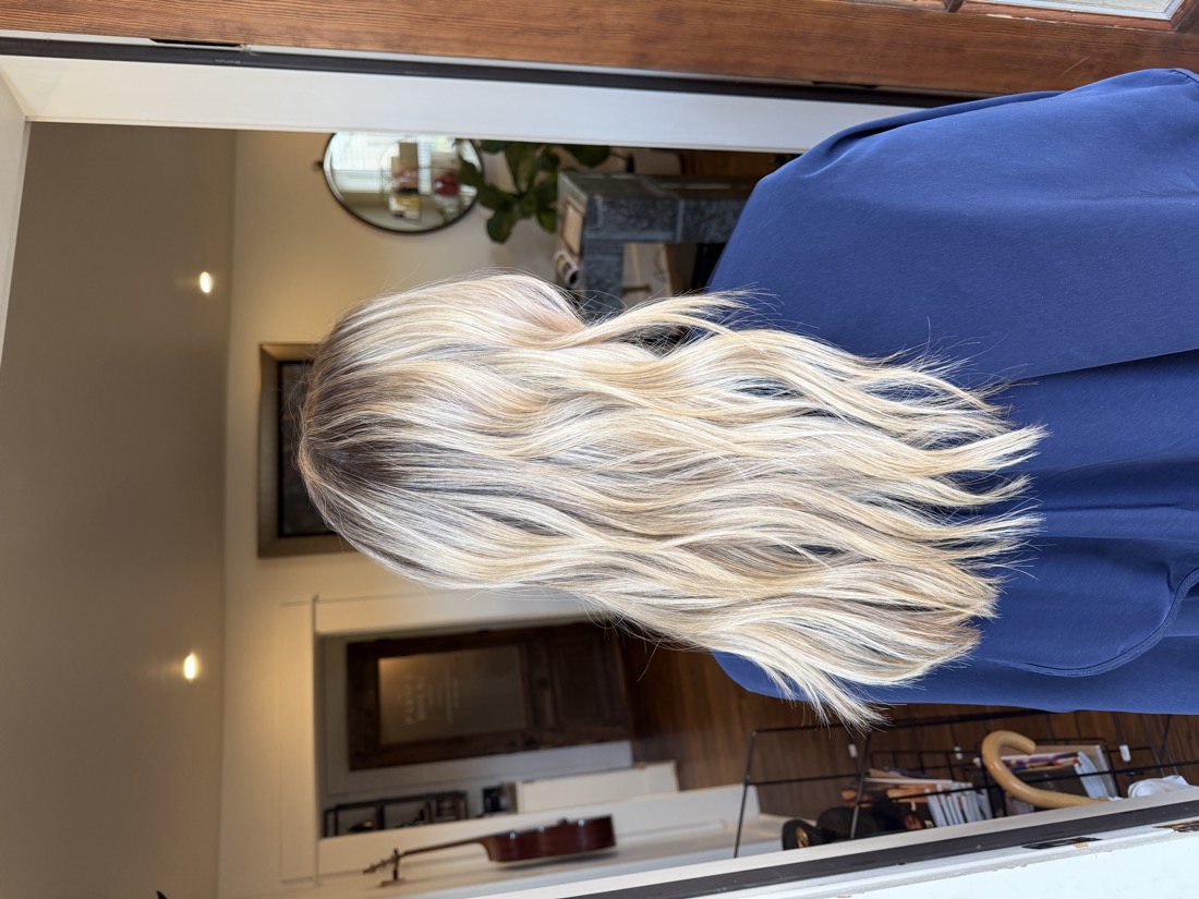 Bright blonde balayage at mid-length, softly finished.